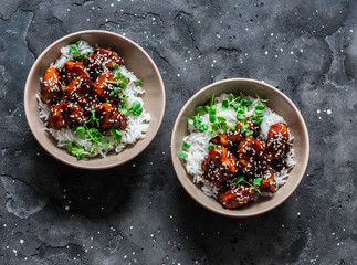 Teriyaki sauce juicy chicken cubes with rice and micro greens - delicious asian style lunch on dark background, top view