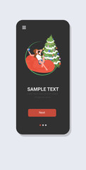 Wall Mural - woman with cellphone sitting on bean bag near christmas tree xmas new year winter holidays celebration concept smartphone screen online mobile app full length vertical vector illustration