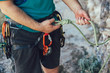 Close-up of climber with climbing equipment, tying knot on climbing harness, preparing for climbing.