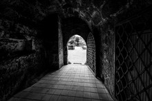 Arched Entrance With Metal Gates To The Fortress. Black And White.