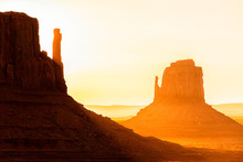 View Closeup Of Famous Mesa Butte Formations With Red Orange Rock Color On Horizon In Monument Valley Canyons During Sunrise In Arizona