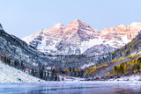Maroon Bells morning sunrise with sunlight on peak in Aspen, Colorado rocky mountain and autumn yellow foliage view closeup and winter snow frozen lake