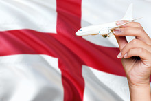 England Travel Concept. Woman Holding A Miniature Plane On National Flag Background. Holiday And Voyage Theme With Copy Space For Text.