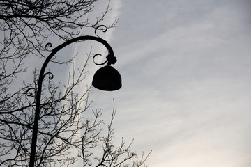 The silhouette of an ornate old lamp post against the evening sky in a public park in Malmö, Sweden