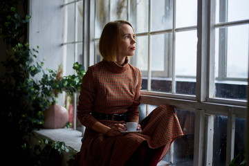 woman with a cup of coffee near a large window