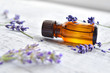 Organic lavender essential oil in dark glass transparent bottle and fresh lavender flowers on wooden background. Aromatherapy treatment.