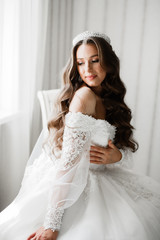 Beautiful bride wearing fashion wedding dress with feathers with luxury delight make-up and hairstyle, studio indoor photo shoot