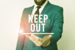 © Artur - Conceptual hand writing showing Keep Out. Concept meaning to stop someone or something from going into a place Danger sign Businessman in blue suite with a tie holds lap top in hands