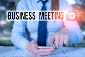 Conceptual hand writing showing Business Meeting. Concept meaning gathering of two or more showing to discuss business ideas Female business person sitting and holding mobile phone