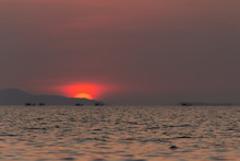 View Of The Evening Sunset. Kathing Lai Beach Banglamung Chonburi Province. The Light Produced Is Bright Red Due To Dust Pollution In The Air Causing The Image To Be Colored.
