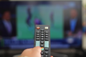 A person with a TV remote controls the remote control to switch channels to watch TV shows.