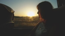 Tourist girl looks through bus window to nature landscape on sunset in move. Sightseeing trip and Travel. Vacation in Montenegro, excursion