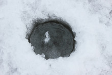 Wormwood, Ice Hole In Frozen Water. A Frozen Hole Drilled In Ice With A Drill. View From Above. A Frozen Hole In A River. Winter Fishing