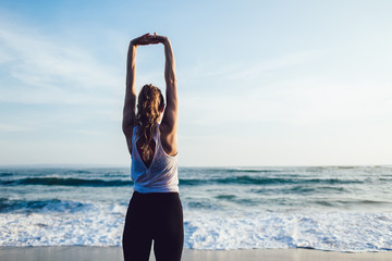 Healthy peaceful woman stretching arms at seaside