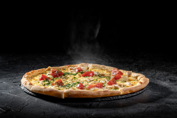 Wall Mural - Hot tasty traditional italian pizza with salami, cheese, tomatoes greens on a dark background