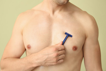 Wall Mural - Handsome young man shaving his body on color background, closeup