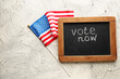 Chalkboard with text VOTE NOW and USA flag on light background