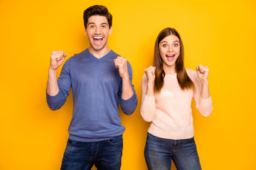 Wall Mural - Portrait of crazy funky romantic spouses win lottery impressed scream wow omg raise fists wear casual style clothes denim jeans isolated over yellow color background