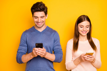 Portrait of positive two people romantic couple use smartphone read social network news wear blue pink sweater isolated over bright color background