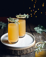 Close up of two glasses of apple cider with festive decoration on wooden table