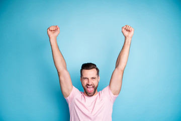 Poster - Photo of attractive guy celebrating ecstatic emotions win lottery money prize yelling loud rejoicing raise fists up wear casual pink t-shirt isolated blue color background