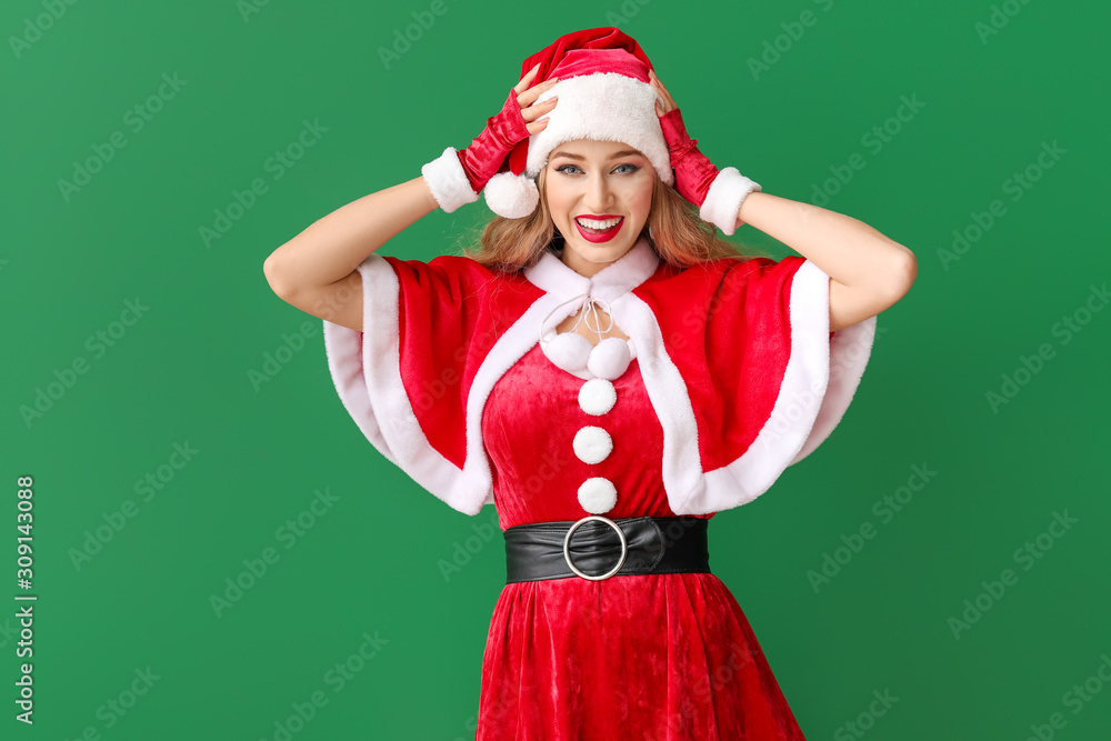 Beautiful young woman dressed as Santa on color background