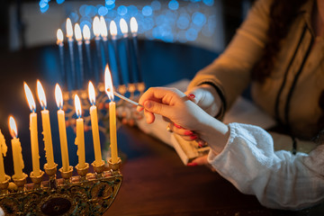 Wall Mural - jewish holiday Chanukah/Hanukkah family selebration. Jewish festival of lights. Children lighting candles on traditional menorah over glitter shiny background