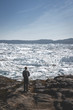 © Mathias - People sitting standing in front of huge glacier wall of ice. Icefjord Ilulissat. Jakobshaven Eqip Sermia Glacier Eqi glacier in Greenland called the calving glacier during midnight sun. Hikers during