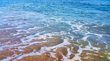 Wall Mural - Sea water with white foam on the coastal sand