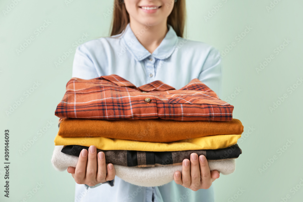 Young woman with clean clothes on color background, closeup