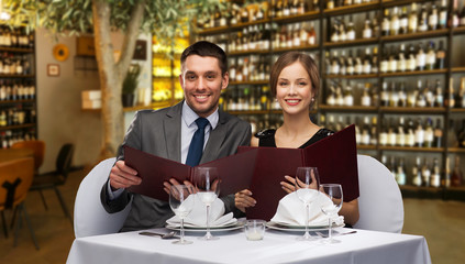 Wall Mural - leisure and luxury concept - smiling couple with menus over restaurant or wine bar background