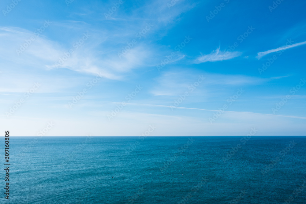 cloudy blue sky leaving for horizon above a blue surface of the sea - obrazy, fototapety, plakaty 