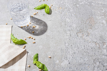 Wall Mural - basil leaves near water, napkin and pine nuts on grey surface