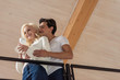 © LIGHTFIELD STUDIOS - Low angle view of smiling man hugging girlfriend with coffee at balcony
