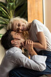 © LIGHTFIELD STUDIOS - Smiling young couple hugging beside window in living room