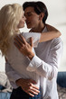 © LIGHTFIELD STUDIOS - Smiling man embracing attractive blonde girlfriend at home