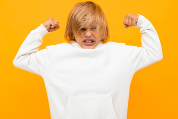 Wall Mural - strong blond boy in a white hoodie on an orange background