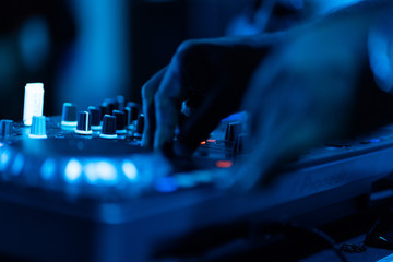 club dj plays music on stage in nightclub.Hand of disc jockey adjusting sound track volume level.Professional audio equipment on music festival