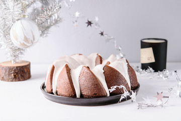 Wall Mural - Homemade Orange Poppy seed Almond Bundt Cake, silver artificial christmas tree and perfumed candle on grey concrete table. Christmas cake. Selective focus