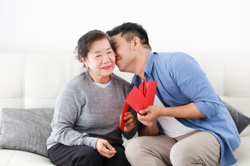 Wall Mural - Chinese New year concept : Asian Senior mother give Red envelope to her son for gift money