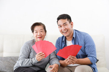 Wall Mural - Chinese New year concept : Asian Senior mother give Red envelope to her son for gift money