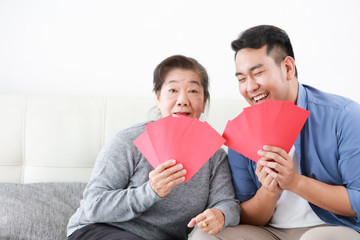 Wall Mural - Chinese New year concept : Asian Senior mother give Red envelope to her son for gift money