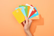 cropped view of woman holding multicolored empty credit cards on peach background