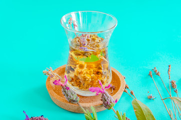 Cup of tea with chamomile and lavender flowers on aqua blue background. Herbal tea, alternative medicine, Ayurveda, aromatherapy. Copy space.