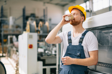 Wall Mural - Portrait of young worker drinking coffee in factory.