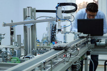 focus on gripper which picks up the product from an automated car and programming engineer at the ba