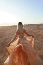 A Woman In A Clay Desert Spins And Dances In A Long Dress.