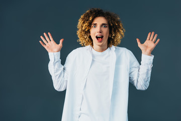 excited stylish curly teenager in total white outfit showing hands isolated on green