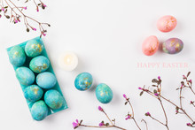 Happy Easter Card. Stylish Minimalistic Composition Of Turquoise With Gold Easter Eggs On A White Background. Candles And Delicate Spring Flowers. Flat Lay, Top View, Copy Space.