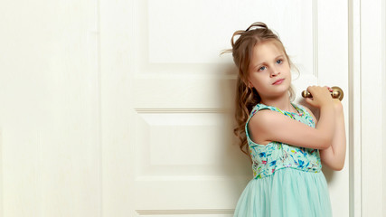 Wall Mural - A little girl is standing by the door.